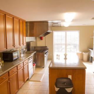 A modern kitchen with wooden cabinets and an island, equipped with appliances.