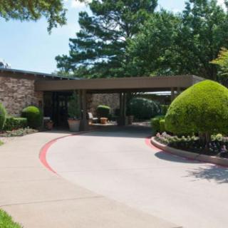 An outdoor view of a building entrance with a circular driveway and well-maintained landscaping.