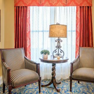 A cozy living room setup with two striped chairs, a lamp on a side table, and decorative curtains.