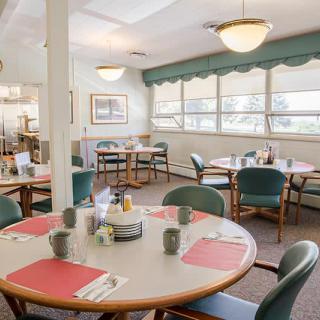 A cozy dining area with neatly arranged tables and chairs, illuminated by overhead lights.