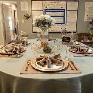 An elegantly set dining table featuring a floral centerpiece and formal place settings.