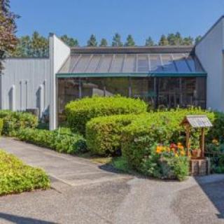 A modern building entrance surrounded by neatly landscaped gardens and pathways.