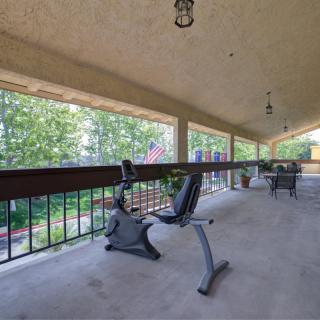 A scenic porch with an exercise bike and outdoor seating.