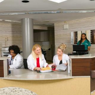 Medical staff at a hospital reception desk engaged in discussion.