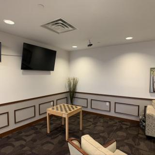 A modern waiting room with a television, seating, and a small table.