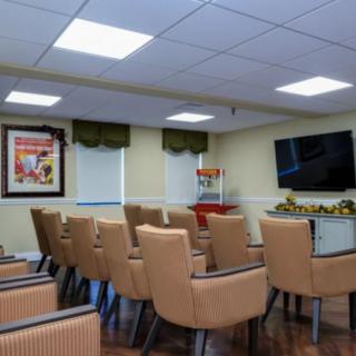 A conference room with rows of comfortable chairs facing a large television.