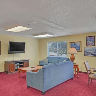 A cozy living room with a sofa, television, and vibrant red carpet.