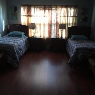 A cozy bedroom with two single beds and sunlight streaming through the window.
