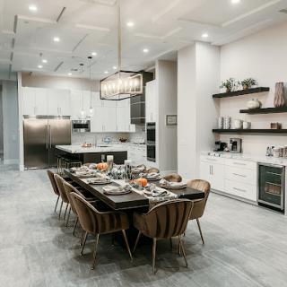 A stylish modern kitchen and dining area featuring a large wooden table, elegant lighting, and sleek cabinetry.