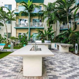 A modern outdoor kitchen area surrounded by tropical greenery and apartment buildings.