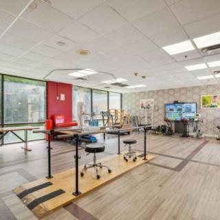 A spacious rehabilitation and physical therapy room equipped with exercise equipment and natural lighting.