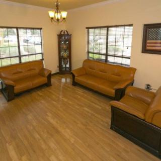 A well-lit living room with brown sofas, a coffee table, and wooden flooring.