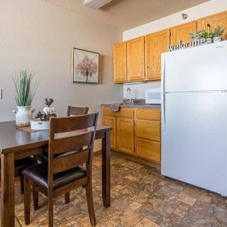 A cozy kitchen with a dining area featuring wooden cabinets, a refrigerator, and a dining table with chairs.