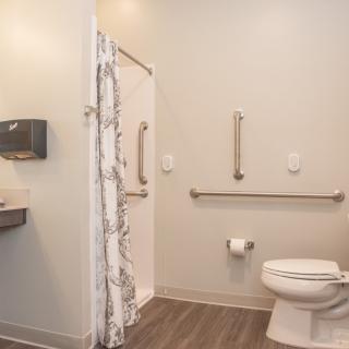 A modern, accessible bathroom featuring grab bars and a roll-in shower.