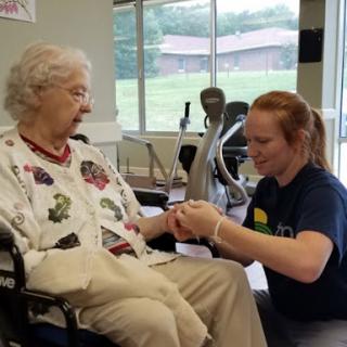 A caregiver assists an elderly individual in a rehabilitation setting.