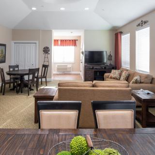 A spacious living room with an open floor plan, featuring a cozy sofa set and a dining area.