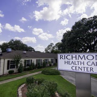 A view of the Richmond Health Care Center, showcasing its exterior and surrounding landscape under a partly cloudy sky.