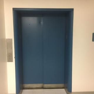 A blue elevator door in a hallway.