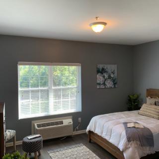 A cozy bedroom with modern decor, featuring a large window that lets in natural light.
