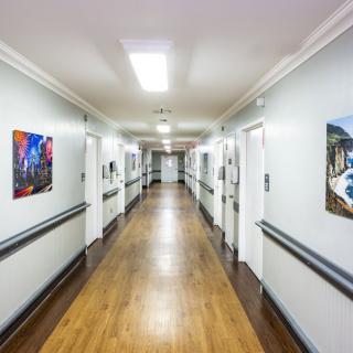 A clean and well-lit hospital corridor adorned with artwork on the walls.