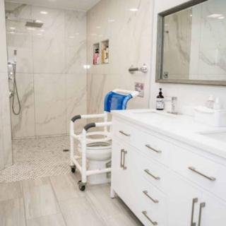 An accessible bathroom with a walk-in shower, vanity, and a wheelchair.