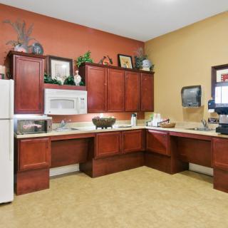 A modern kitchen with wooden cabinets, a white refrigerator, and a microwave.