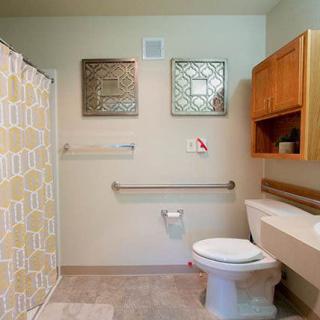 A clean and organized bathroom featuring a toilet, sink, shower curtain, and wall-mounted cabinet.