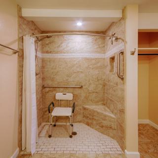 An accessible walk-in shower with a shower chair and safety handrails.