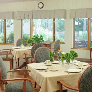 A well-lit dining room with neatly arranged tables and chairs, adorned with plants and set for a meal.