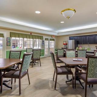 A spacious dining area with multiple tables and chairs, featuring a kitchen in the background.