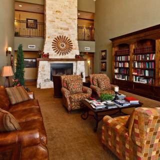 A cozy living room featuring a large fireplace, comfortable seating, and bookshelves filled with books.