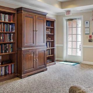 A cozy library corner with wooden bookshelves and a carpeted floor.