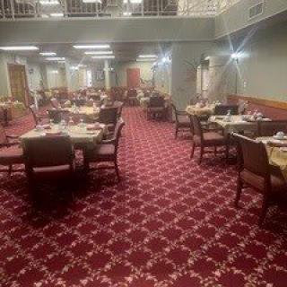 An empty dining room with neatly arranged tables and chairs on a patterned carpet.