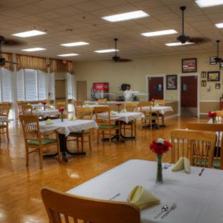 A spacious and inviting dining area, set for guests with neatly arranged tables and soft lighting.