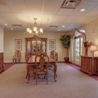 A spacious dining room featuring elegant wooden furniture and a classic chandelier.