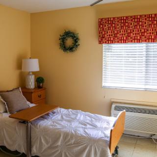 A cozy and well-lit patient room featuring two beds, a bedside lamp, and cheerful decorations.