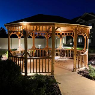 A beautifully lit wooden gazebo in a garden setting at night.