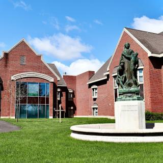 A scenic view of a brick building featuring a prominent statue in the foreground.