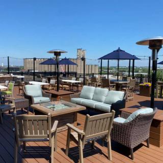 A spacious rooftop patio with comfortable seating and umbrellas under a clear blue sky.