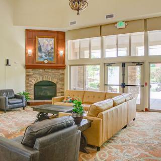 A cozy lobby area with comfortable seating, a fireplace, and large windows letting in natural light.