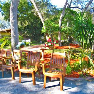 A tranquil garden with wooden chairs and lush greenery.