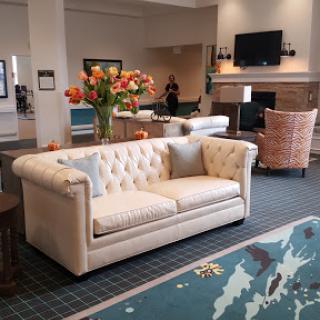 A stylish and inviting hotel lobby featuring a plush sofa, vibrant floral arrangement, and cozy seating.