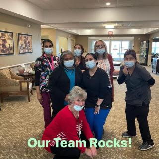A group of team members posing together, wearing masks, with the text 'Our Team Rocks!'