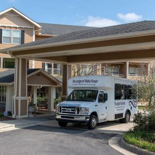 A van parked under the entrance awning of a large building on a sunny day.