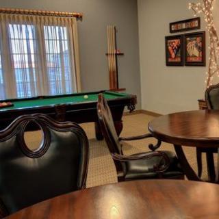 A cozy game room featuring a pool table, leather chairs, and round tables.