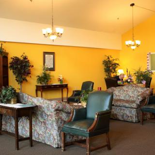 A cozy lounge area featuring floral patterned sofas, green chairs, and bright yellow walls.
