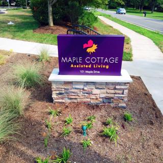 Entrance sign for Maple Cottage Assisted Living surrounded by landscaping.