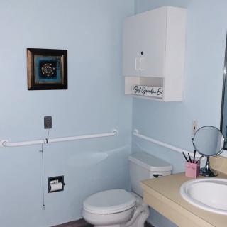 A well-organized bathroom with a toilet, sink, and mirror beneath light blue walls.