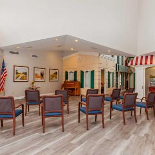 A community meeting area with arranged chairs, a piano, and artwork on the walls.