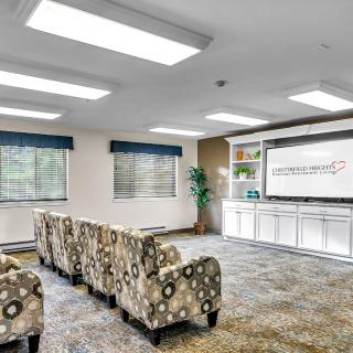 A modern conference room with patterned chairs and a large screen.